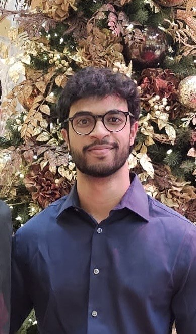 Saaketh Chenna smiling, wearing glasses and a navy shirt